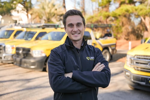 Jeffrey Linta II, President of Linta Roofing, in front of the Linta Roofing fleet in Myrtle Beach
