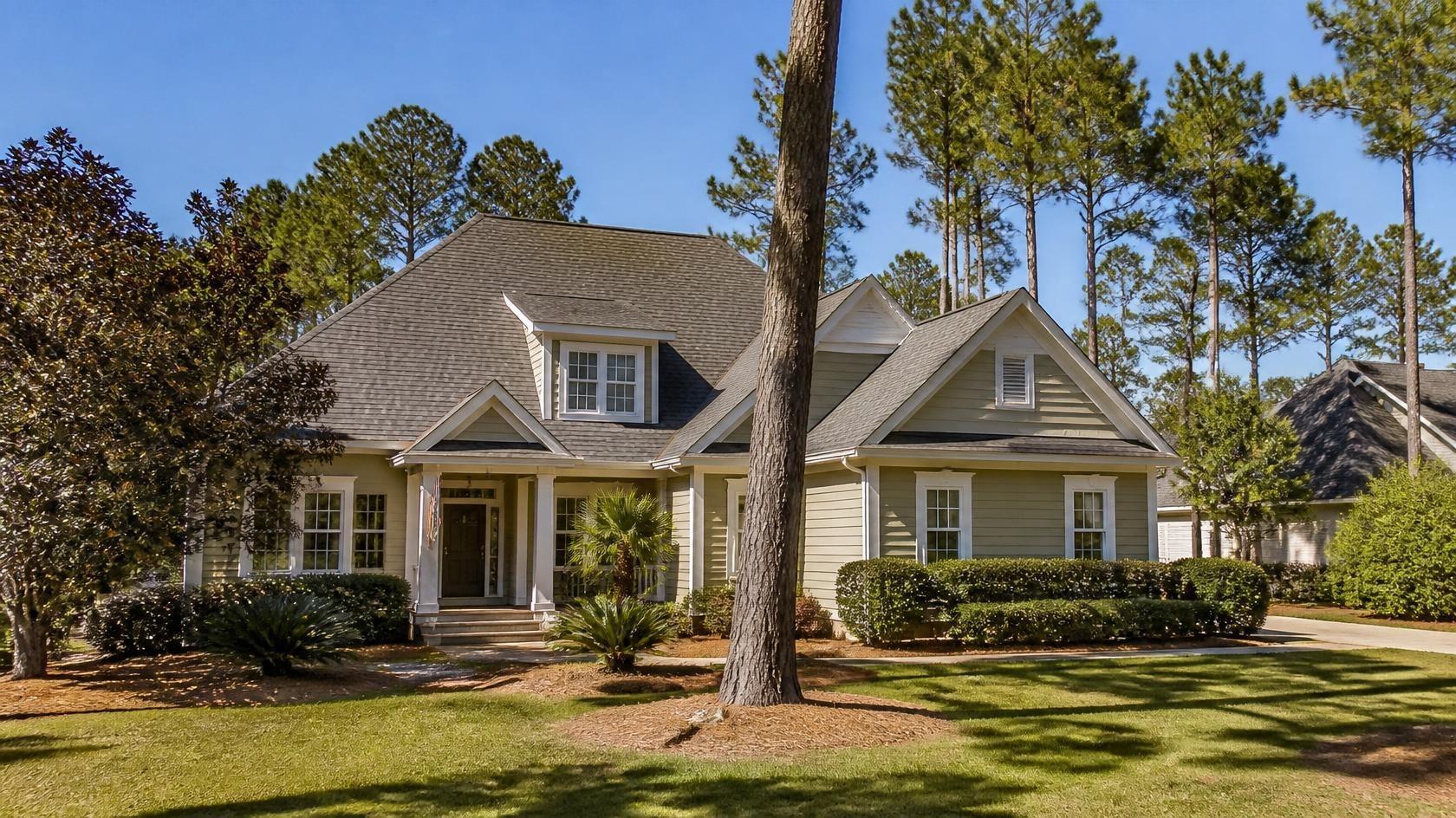 Home with a gray asphalt shingle roof surrounded by tall pine trees