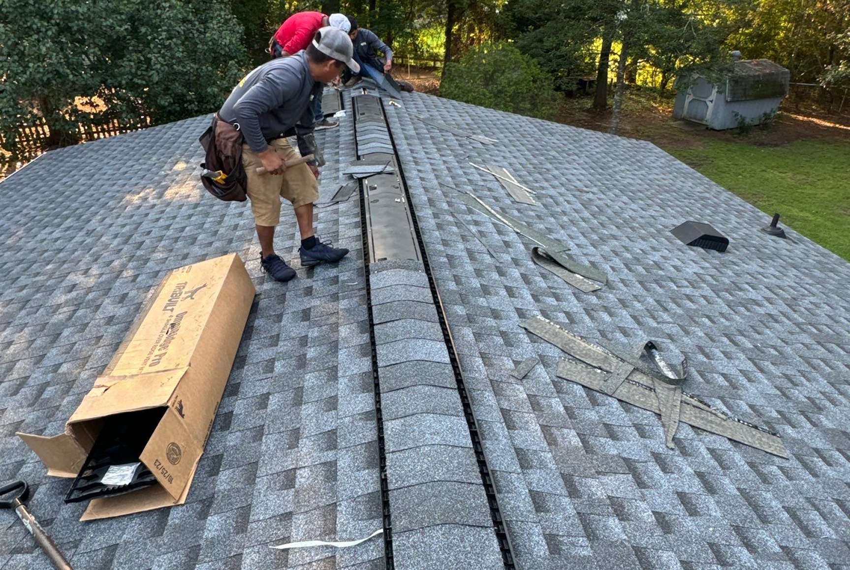 Linta Roofing crew installing a ridge vent on a new gray shingle roof