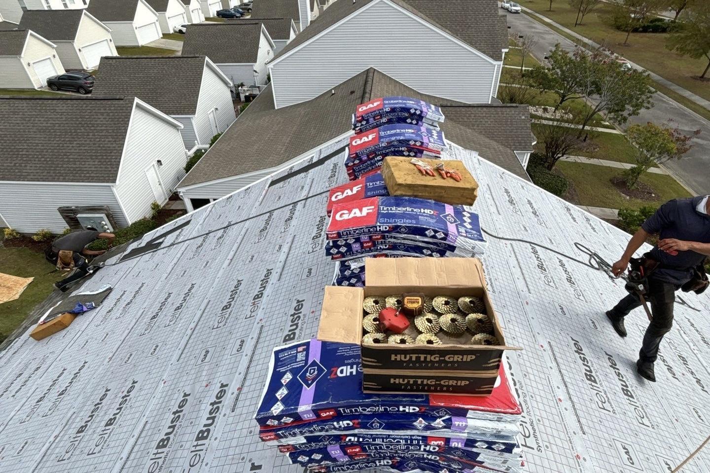 Bundles of GAF Timberline HDZ shingles staged on a roof covered in new synthetic underlayment