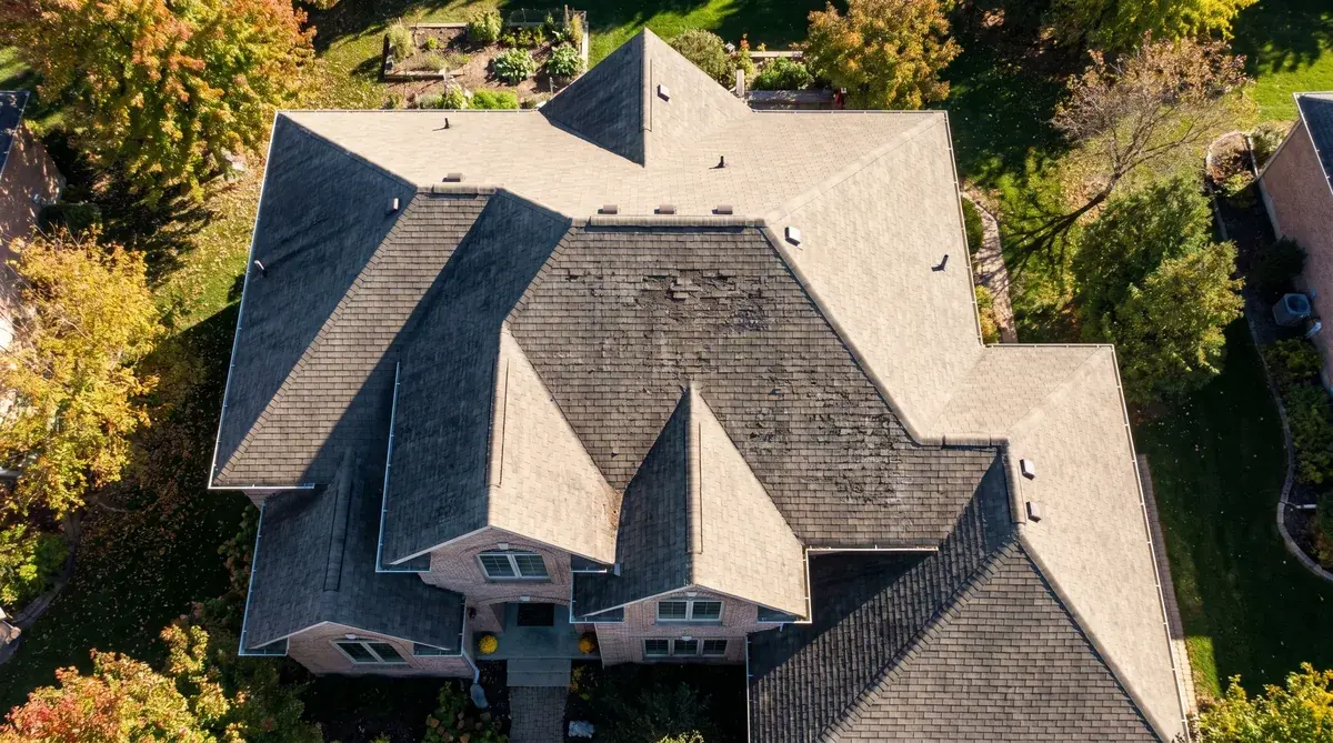 aerial view of a house showing different levels of granule loss on various roof slopes, with south-facing areas showing more wear than north-facing areas