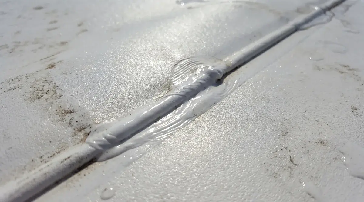 Close-up view of PVC roofing membrane showing heat-welded seams and white reflective surface texture