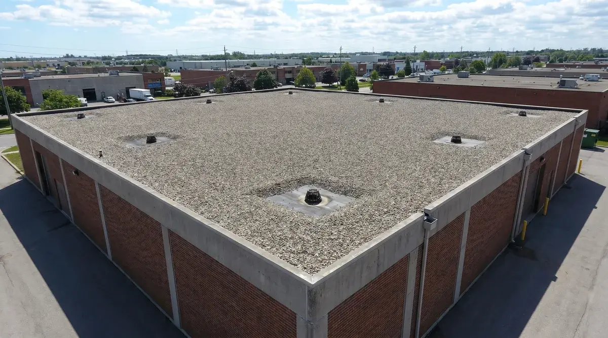 Commercial building with tar and gravel roof showing proper gravel coverage and drainage system